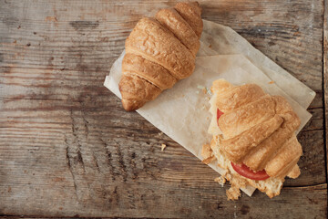 morning breakfast of croissants. Two croissants on a wooden background. Hearty croissant with tomato and cheese. Close-up with a copy space for the text. Horizontal orientation.