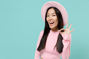 Happy smiling fun young brunette asian woman 20s wears pink clothes hat showing okay ok gesture...