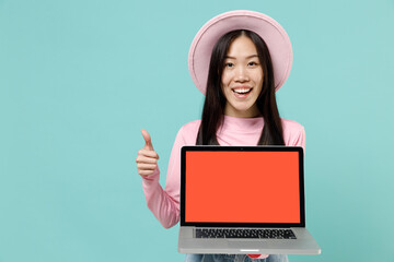 Fun young brunette asian woman 20s wear pink clothes hold use work on laptop pc computer with blank screen workspace area show thumb up gesture isolated pastel blue color background studio portrait.