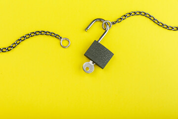 Fototapeta na wymiar unlocked padlock with chain on yellow background with copy space