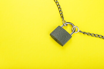 Fototapeta na wymiar locked padlock and chain on yellow background with copy space