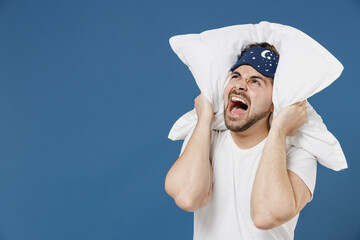 Young man in pajama jam sleep mask rest relax at home lying on pillow cover ears from neighbors...