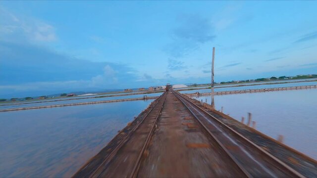 Aerial forward FPV racing drone flight over salt flats old rail conveyor, Bani. Dominican Republic