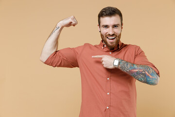 Strong sporty fitness assured tatooed young brunet man 20s with earrings wear apricot shirt show...