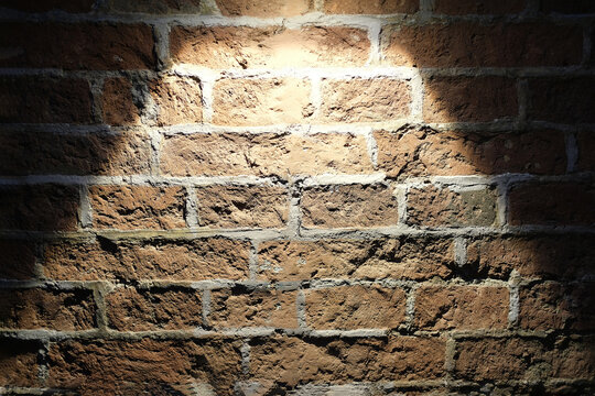 Brick wall covered with a lamp, light on a brick surface