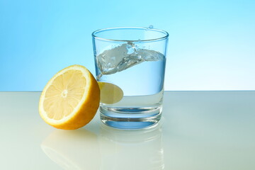 effervescent vitamin C tablet dissolves in water. a glass of water, effervescent tablet and citrus fruit on blue background. vitamin C concept