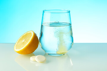 effervescent vitamin C tablet dissolves in water. a glass of water, effervescent tablet and citrus...