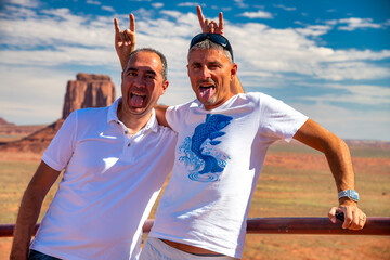 Couple of male friends making grimaces and joking with the wonderful Monument Valley scenario in...