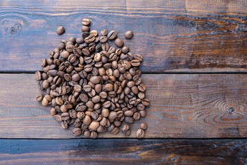 Roasted coffee grains on a wooden table close-up.