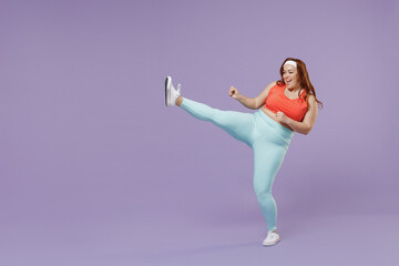 Full length young chubby overweight plus size big fat fit woman wear red top warm up training doing stretch exercise for legs isolated on purple background home gym. Workout sport motivation concept.