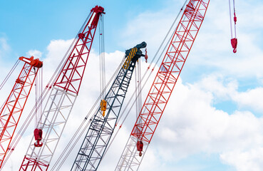 Crawler crane against blue sky and white clouds. Real estate industry. Red crawler crane use reel lift up equipment in construction site. Crane for rent. Crane dealership for construction business. - Powered by Adobe