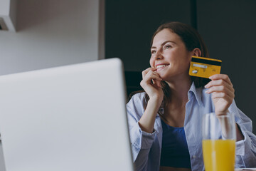 bottom view young housewife woman in blue clothes use laptop pc computer credit bank card shopping online order delivery book tour cook food in light kitchen at home. Healthy diet lifestyle concept.