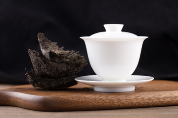 White porcelain tureen and brick tea tea leaves on cutting board