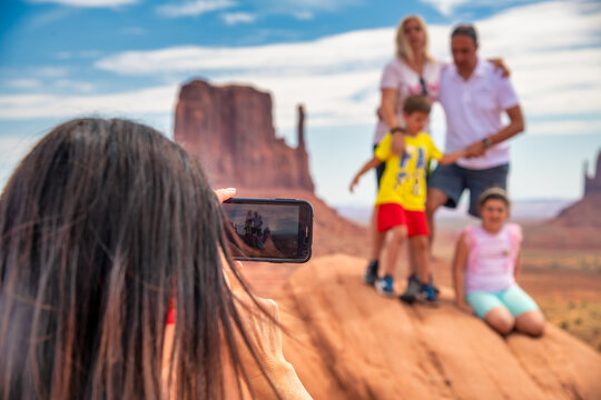 Female Photographer Taking Pictures Of A Family Visiting Monument Valley.