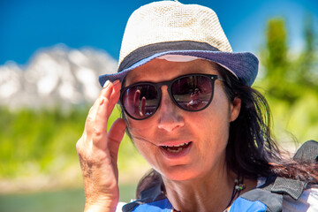 Happy woman relaxing on a boat tour along mountain river on a beautiful sunny day.