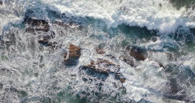 An aerial footage of strong waves crashing on the rocks on the coast in 4K