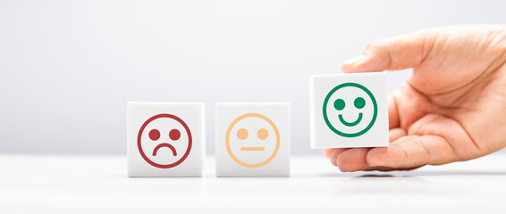 happy smiley face in white block on hand for feedback rating and positive customer review and world mental health day