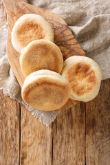 Freshly baked English muffins close-up in a board on the table. vertical top view from above