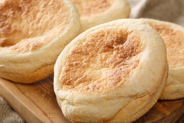 Delicious authentic English muffin buns close-up on a wooden board on the table. horizontal