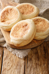 Homemade English muffins buns close-up in a board on the table. vertical