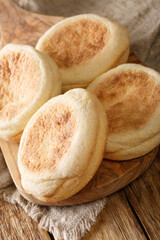 Freshly baked English muffins close-up in a board on the table. vertical