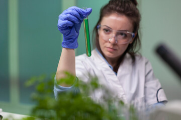 Chemist researcher woman holding test tube with dna liquid observing genetic mutation on sample...