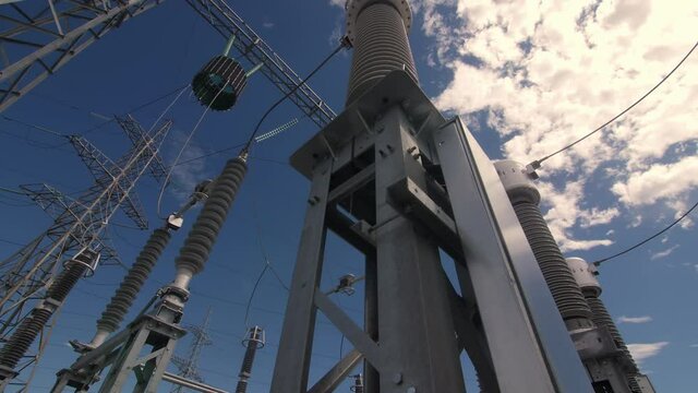 Glass and ceramic insulators on electricity production substation switchyard under blue sky close low angle shot