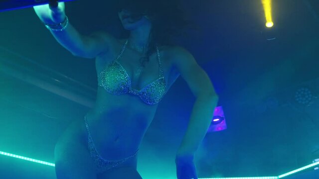 Girl in lingerie dancing to thClose-up of a girl in lingerie dancing to the beat of the music. She is dressed in yellow underwear and is surrounded by club floodlights. High quality 4k footage