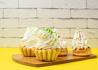 Cake with protein cream on a kitchen wooden board, white cup with tea, brick wall background. Food, baking and cooking concept. Side view. Blurred background. Focus on the foreground.