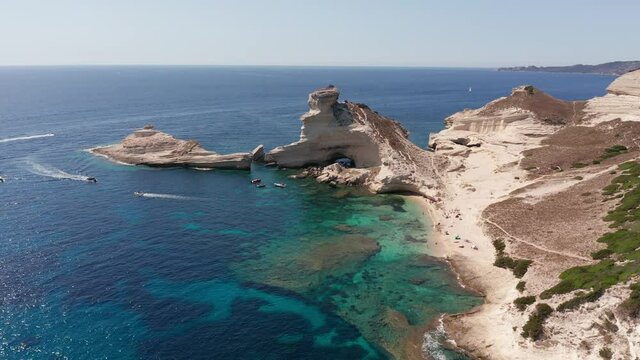 Aerial view of white bluff beach on bay on the coastline with waves in the blue sea. Aerial footage of he immense white cliff on the turquoise sea with boat near Bonifacio Corsica