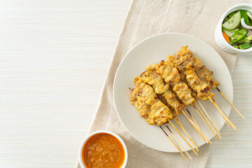 Pork satay with peanut sauce pickles which are cucumber slices and onions in vinegar