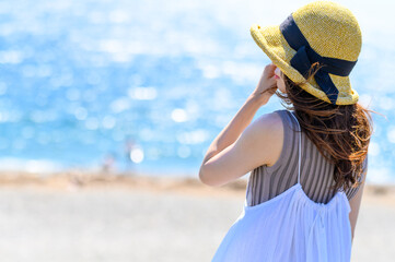 Fototapeta premium 浜辺で遠くを見つめる女性