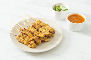Pork satay with peanut sauce pickles which are cucumber slices and onions in vinegar