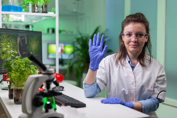 Pov of chemist woman in white coat analyzing with biologists team during online videocall meeting while sitting in microbiology lab. Specialist researching genetic mutation developing dna test.