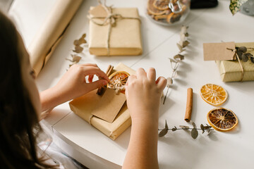 Holiday preparation and gift wrapping with craft paper on white table. Gift wrapped in brown paper...