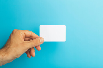 Empty plastic card in hand on colored background. ID or credit money card isolate