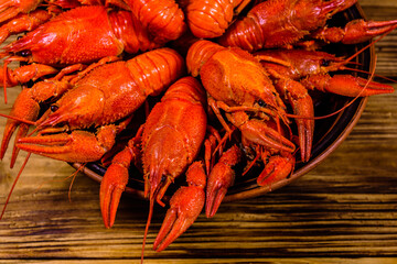 Plate with boiled crayfishes on wooden table