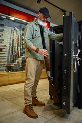 Bearded male hunter buying gun locker in store