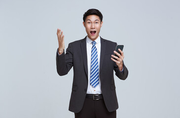 Handsome and friendly face asian businessman excited in formal suit his using smartphone on white background studio shot.