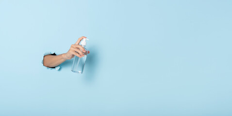 Hand holding alcohol gel or antibacterial soap sanitizer on blue background. Hygiene concept. prevent the spread of germs and bacteria and avoid infections corona virus