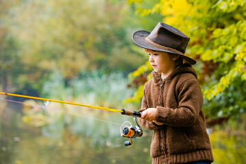 Kids fishing by mountain lake in autumn.