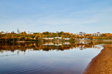 Obraz premium Natural view of the landscape with a lake or river and a city on the other side on the yellow shore in autumn day with blue sky