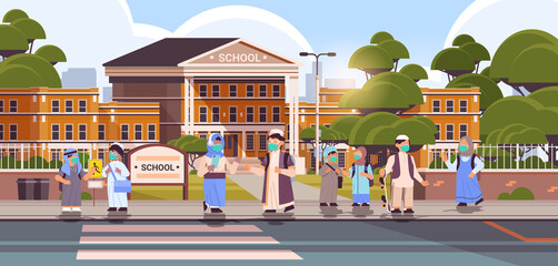 Obraz na płótnie Canvas arabic schoolchildren wearing masks to prevent coronavirus pandemic pupils standing together near school building