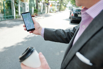 Close-up of businessman holding mobile phone with GPS map and searching for the way in the city