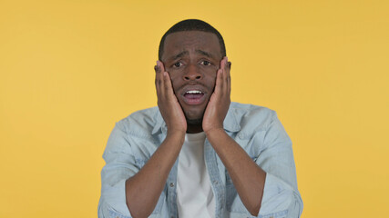 Young African Man Reacting to Loss, Yellow Background 