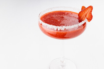 Bright fresh strawberry margarita cocktail with sugar rim, fruit slices on white wood board, top view, closeup.