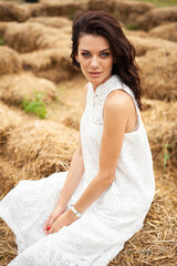 Beautiful woman wearing white dress on dry grass