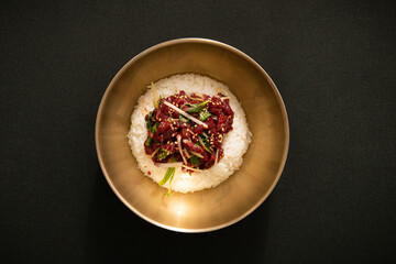 검은색배경에 육회비빔밥이 그릇에 담겨있다.