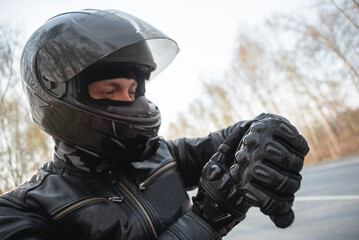 Motorbiker is checking the time on his wrist watch.