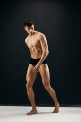 Naklejka premium man in black panties with naked muscular body dark background